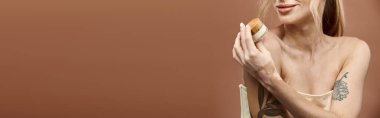 Vitiligo 'su olan genç bir kadın bej arka planda cildine krem sürüyor..