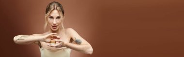 Vitiligo 'su olan genç bir kadın elinde krema kavanozunu tutuyor ve doğrudan kameraya bakıyor..