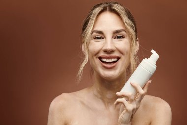 Vitiligo 'su olan genç bir kadın elinde bir cilt bakımı ürünü tutarken gülümsüyor..