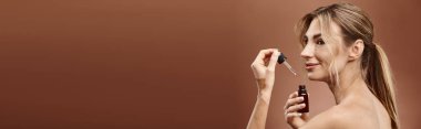 Vitiligo 'su olan genç bir kadın bej bir arkaplana karşı yüzüne bir cilt ürünü sürüyor..