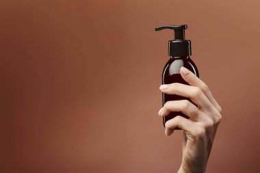 A young girl with vitiligo holds a skincare product bottle in front of a beige background. clipart