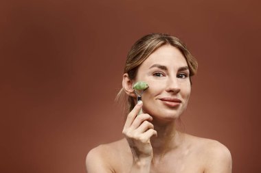 Vitiligo 'su olan genç bir kadın yüzüne yeşim bir silindir takıyor. Parlak cilt için bir cilt sergiliyor..
