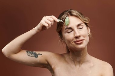Vitiligo 'su olan genç bir kadın, alnında yeşim taşıyla rahatlatıcı bir güzellik gösterisi yapıyor..