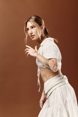 Vitiligo 'su olan genç bir kadın bej arka planda beyaz yaz kıyafetleri içinde güven içinde poz veriyor..