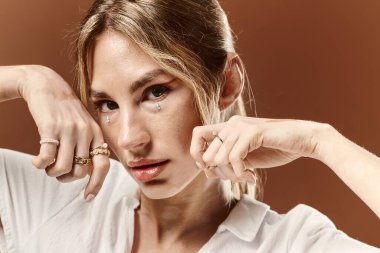 Vitiligo 'su olan genç bir kadın, bej bir arka plana karşı eşsiz güzelliğini sergileyen beyaz bir yaz elbisesi içinde güven içinde poz veriyor..