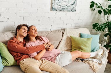 Protez bacaklı bir kadın, erkek arkadaşıyla sıcak bir oturma odasında kanepede sarılıyor..