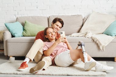 Genç bir çift yerde rahatlar, birbirlerine eşlik ederler ve bir an için kahkahalarla gülerler..