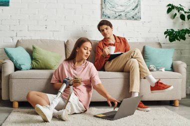 Dizüstü bilgisayarı protez olan bir kadın, erkek arkadaşı koltukta..