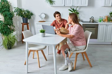 Protez bacaklı bir kadın, erkek arkadaşıyla mutfak masasında oturur..