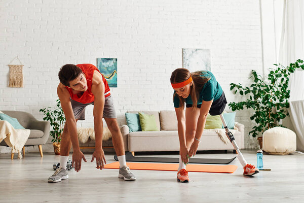 Женщина с протезной ногой растягивается рядом со своим парнем в их доме..