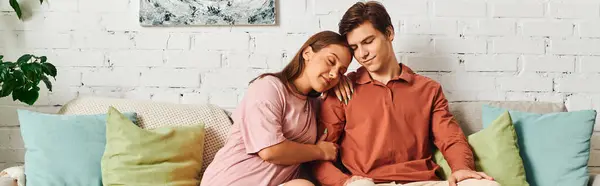 stock image A woman rests her head on her boyfriends shoulder while sitting on a couch.