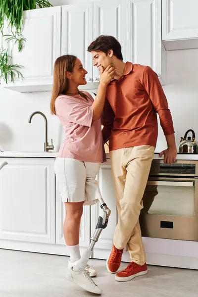 stock image A woman with a prosthetic leg and her boyfriend share a tender moment in their kitchen.