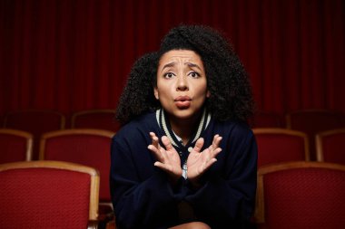 A young African American woman in a theater seat, reacting to the movie. clipart