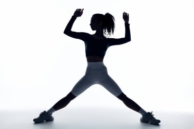 A young Black woman in athletic wear stretches her legs and arms in a dynamic pose. clipart