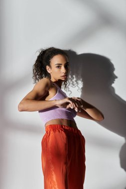 Moda kıyafetli genç bir kadın beyaz bir arkaplanda poz veriyor..