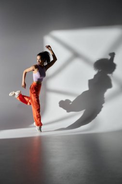 Stüdyoda dans eden genç bir kadın moda tarzını ve özgüvenini sergiliyor..