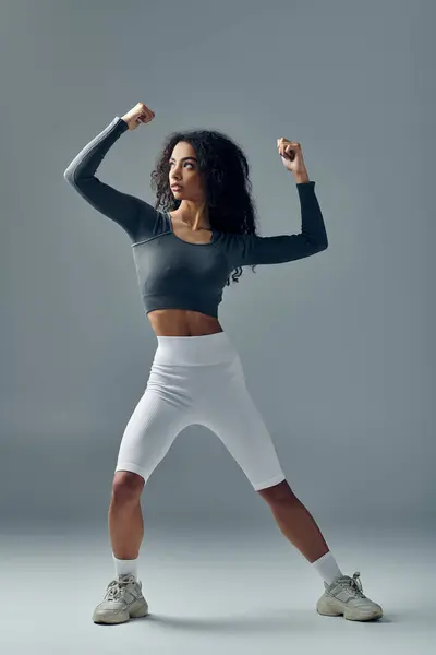 stock image A young Black woman in athletic wear performs a dynamic pose during a fitness session.