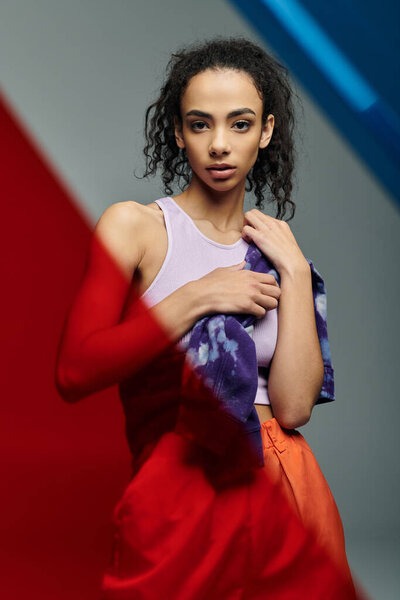 Спортивная женщина в студии, держащая полотенце, на красочном фоне. Она кажется решительной, но расслабленной..