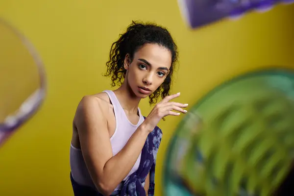 stock image A young woman with curly hair and a confident expression stands in a studio, her vibrant style shining through.