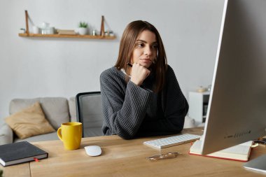 Genç bir kadın evindeki bir masada oturup bilgisayar ekranına bakıyor..