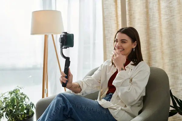 stock image A young woman vlogs about her day, laughing while filming with a phone stabilizer.