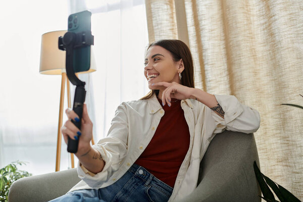 Молодая женщина делает видеоблоги, держа в руках стабилизатор смартфона, снимая контент для своего бизнеса в области цифрового маркетинга.