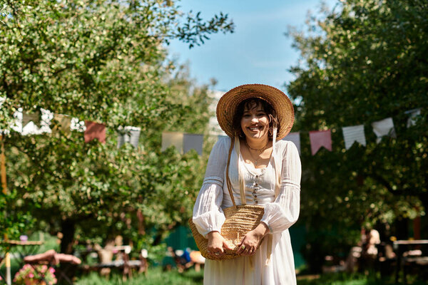 A young woman in a white blouse and straw hat smiles warmly, standing amidst a lush summer garden.