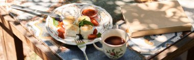 Genç bir kadın güneşli bir bahçede hafif bir brunch 'ın tadını çıkarıyor..