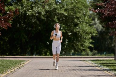 Güneşli bir günde, Vitiligo 'su olan genç bir kadın, beyaz etek ve kulaklık takarak güvenli bir şekilde parkta koşuyor..