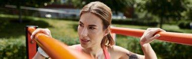 Vitiligo 'lu genç bir kadın, pembe bir bluz ve etek giyiyor, açık havada parkta barfiks egzersizi yapıyor..