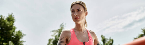 Молодая женщина с витилиго работает в розовый топ урожая и активировать, ее татуировка видна, в парке в солнечный день.