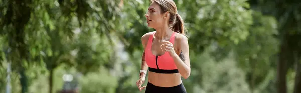 stock image A young woman with vitiligo runs through a park, wearing a pink sports bra and black leggings.