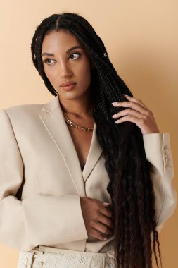 A young woman with long black braids poses in a cream blazer. clipart