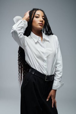 A young woman poses in a white button-down shirt against a grey background. clipart