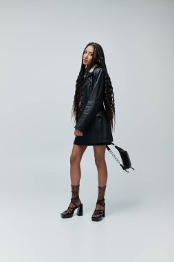 Tarz sahibi genç bir kadın siyah deri ceket ve etekle poz veriyor. Kendinden emin bakışları büyüleyici..