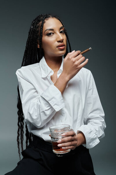 A woman in a white shirt holds a glass and a cigar, staring intently into the distance.