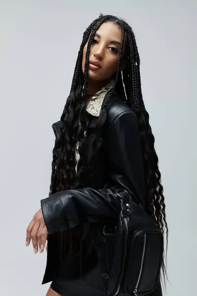 stock image A young African American woman poses in a black leather jacket and skirt, an animal print shirt peeking out from under the collar.