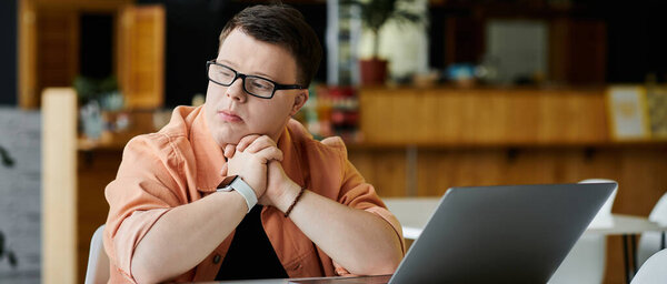 A man works on his laptop at a cafe, taking advantage of the space and atmosphere for remote work.