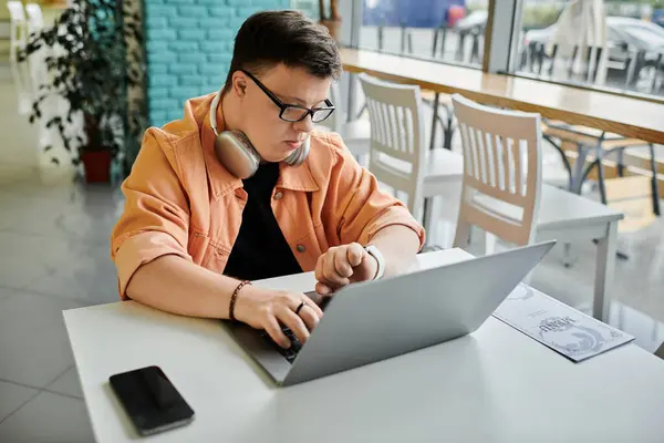 stock image A man with Down syndrome works on his laptop in a cafe, surrounded by the energy of everyday life.