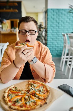 Bir adam bir kafede pizza diliminden hoşlanır, çeşitlilik ve kapsama gösterir..