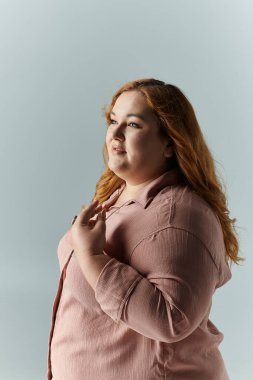Pembe gömlekli bir kadın elini göğsüne koyup düşünceli bir ifadeyle yukarı bakar..
