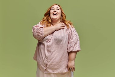 Pembe bluzlu bir kadın yukarı bakarken gülüyor..