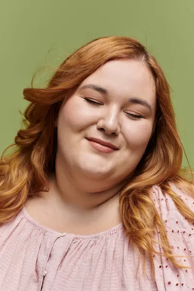 stock image A beautiful, plus-size woman in an elegant pink blouse smiles softly with her eyes closed.