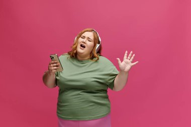 Bir kadın elinde akıllı bir telefonla şarkıya eşlik eder..