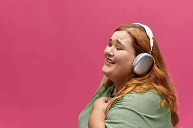 Büyük beden bir kadın gülümser ve müzik dinler, neşesi dışarıya yayılır..