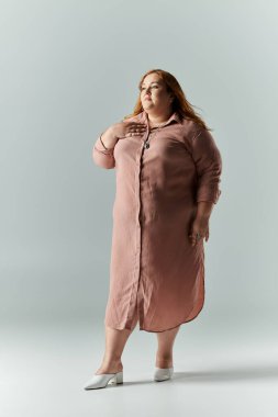 A plus size woman in a pink dress stands confidently in front of a plain backdrop. clipart