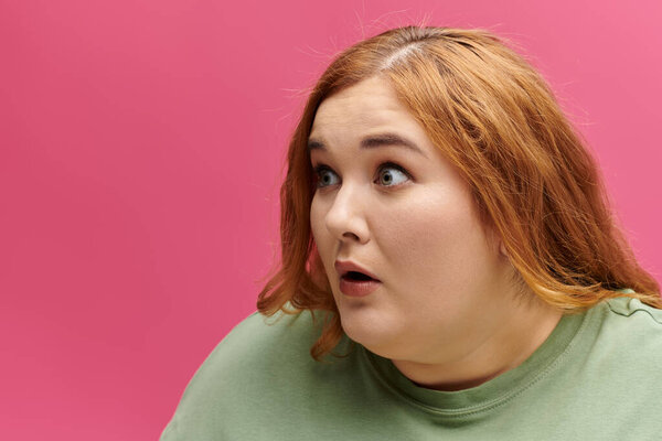 A woman with red hair looks surprised, her mouth slightly open.