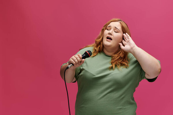 A woman with red hair sings into a microphone, her hand cupped behind her ear.