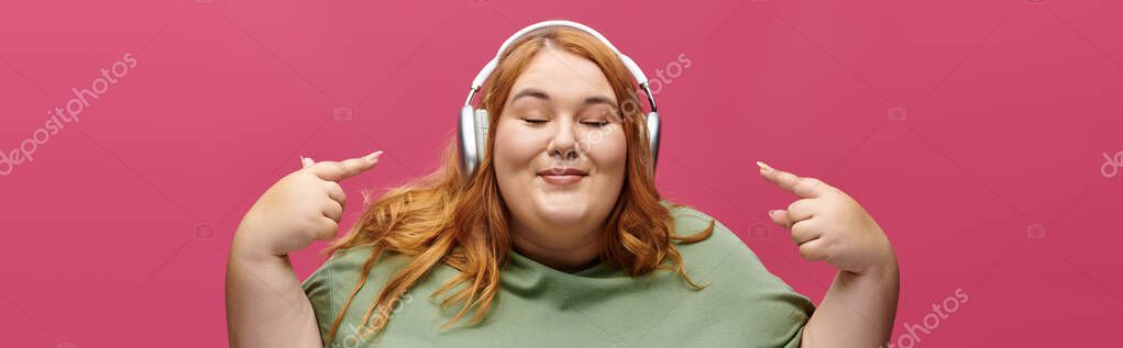 A plus size woman smiles as she listen to music with headphones on.