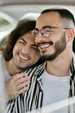 İki adam, mutlu bir şekilde arabada gülüyorlar..